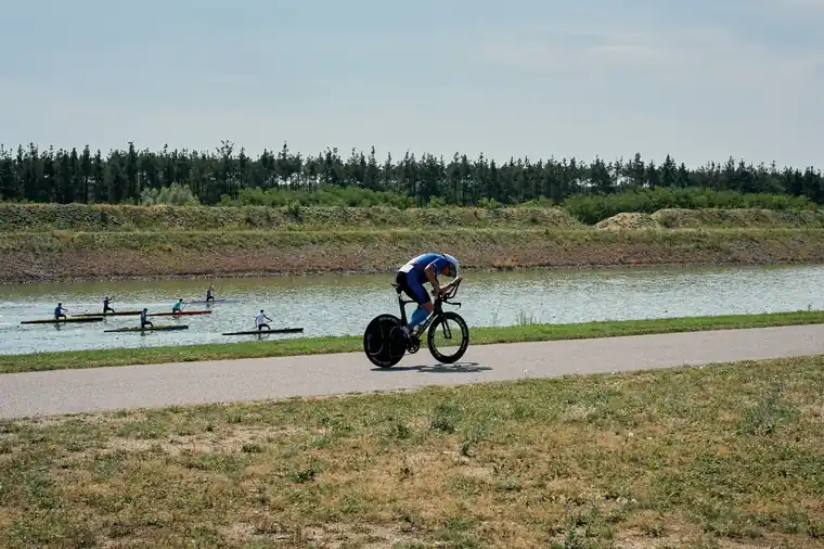 Cycling beside the canal with rowers on the water